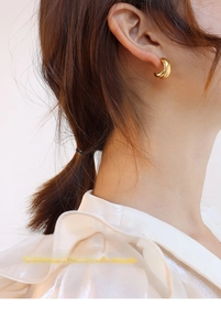 Detail of elegant gold-plated 18K stainless steel cross hoop earring worn by a model