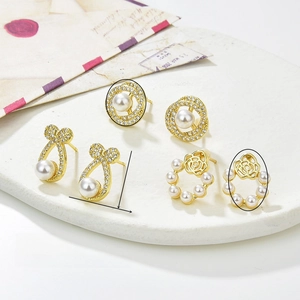 Macro view of zircon-inlaid pearl stud earrings on a marble tray with vintage props
