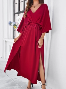 Detail of red V-neck maxi dress with waist tie and side slit on a professional model