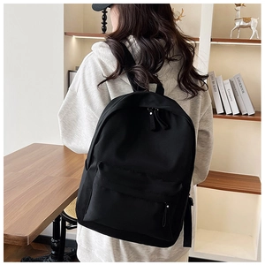 Detailed back view of a black lightweight nylon backpack with adjustable straps on a model