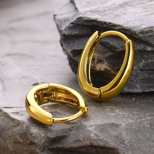 Detailed view of 18k gold plated oval hoop earrings on a textured grey stone