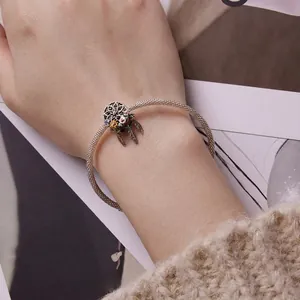 Silver dreamcatcher charm bracelet with floral design and metal feathers on wrist
