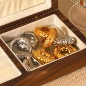 Detail view of gold and silver C-shaped textured ear cuffs in a wooden jewelry box