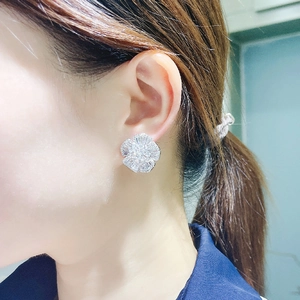 Close-up of a large camellia flower stud earring with sparkling cubic zirconia on ear