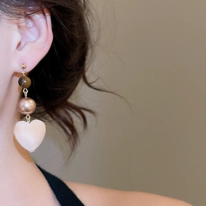 Close-up of elegant long heart drop earrings with tiger eye beads and rose gold pearls
