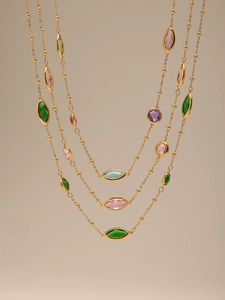 Détail de colliers dorés superposés avec pierres colorées et perles rondes
