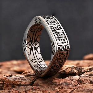 Detail of square vintage silver ring featuring engraved geometric patterns on wood