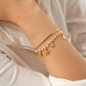 Set bracciale dorato oceano con ciondoli stella marina conchiglia e perle sul polso