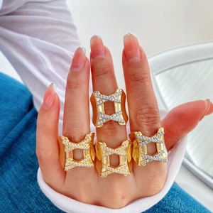 Detailed view of wide gold-plated criss-cross ring with pavé-set cubic zirconia on hand