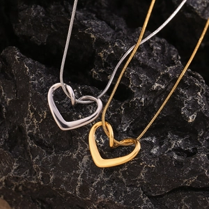 Macro shot of gold and silver heart pendants on elegant snake chains over black rock