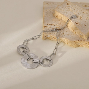 Macro shot of silver stainless steel bracelet featuring textured circular charms and oval links