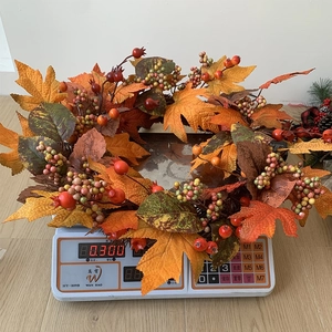 Detail showing the 300g weight of the autumn pumpkin maple leaf berry wreath on a scale