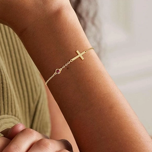 Elegant gold cross bracelet for women featuring a minimalist red gemstone inlay on wrist