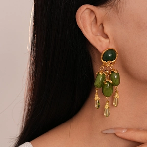 Gros plan de boucles d'oreilles pendantes en résine vert olive avec franges dorées