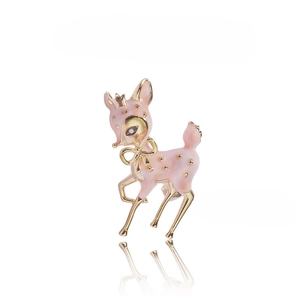 Close-up of pink enamel deer brooch with golden bow and crown on white background