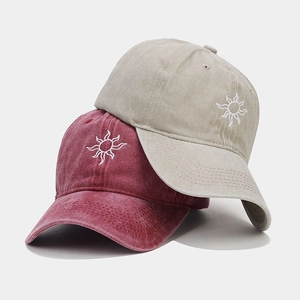 Detail of vintage sun embroidery on washed red and khaki cotton baseball caps