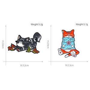 Creative enamel cat pins featuring a ginger cat in a sweater and a calico cat with a leaf