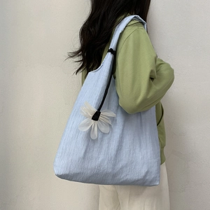 Light blue pleated canvas tote bag with 3D white flower decor worn by model