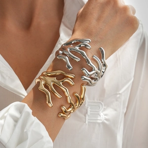 Detail of minimalist fluid art gold and silver open cuff bracelets on model wrist