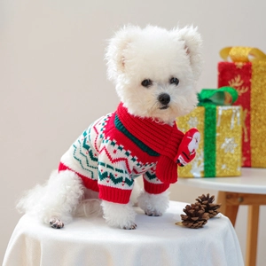 Detail view of festive red knitted Christmas sweater and scarf set on a white puppy