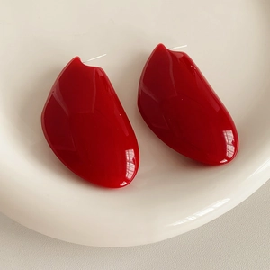 Gros plan de boucles d'oreilles géométriques en résine rouge sur un plat en céramique