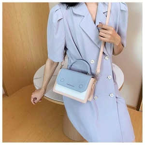 Detail view of contrast color leather handbag with fashion text and metal rivet buckles