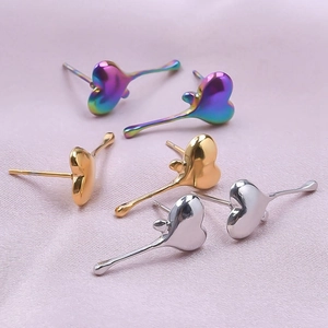 Macro shot of heart-shaped stainless steel earrings in gold, silver and rainbow on silk