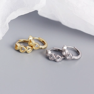 Detailed close-up of hollow heart link earrings in polished gold and silver finishes
