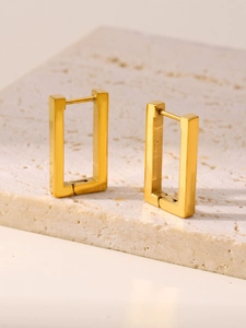Detail shot of 18K gold plated rectangular geometric hoop earrings on a stone base