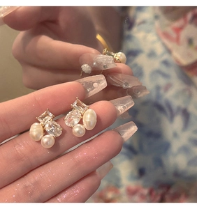 Close-up of geometric gold earrings with baroque pearls and sparkling zircon stones