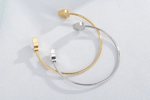 Detail of gold and silver stainless steel open bracelets with heart shaped ends