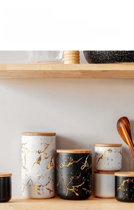 Detail of Nordic matte ceramic jars with gold marble veins and airtight bamboo lids