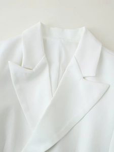 Gros plan du revers d'un blazer blanc montrant les coutures et la texture du tissu sergé