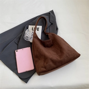 Detailed top view of a brown suede tote bag styled with office lifestyle accessories