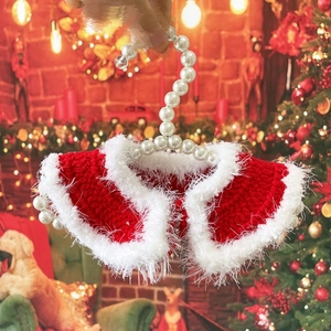 Close-up of red and white knitted Christmas pet shawl with pearl hanger on festive background