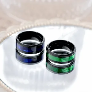 Fashionable titanium steel rings for men in green and blue shown on a reflective mirror