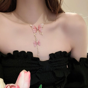 Detail of necklace featuring pink tulle butterfly pendants with gold fringe and diamond accents