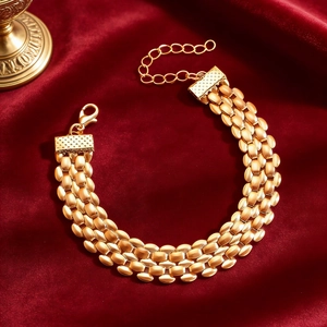 Close-up of gold-plated tank chain bracelet with lobster clasp on red velvet fabric