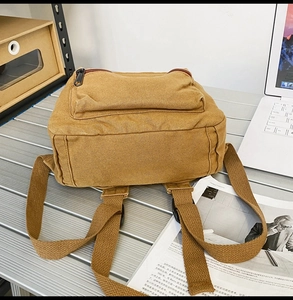 Draufsicht auf Retro-Canvas-Rucksack mit Reißverschlusstasche auf einem Schreibtisch