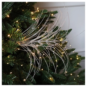Close-up of silver glitter branch pick ornament on a glowing Christmas tree