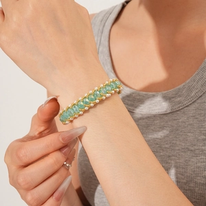 Detailed shot of beaded bracelet with green crystal pearls and gold accents on wrist