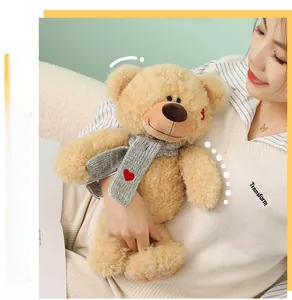 Detalle de oso de peluche con bufanda gris y corazón rojo, muestra textura muy suave