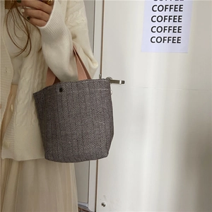 Detailed close-up of herringbone pattern canvas tote bag with pink straps and button closure