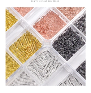 Detailed view of mixed gold silver and black mini metal beads for nail art in a grid box