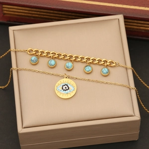 Close-up of golden double-layer necklace with turquoise and evil eye in a beige gift box