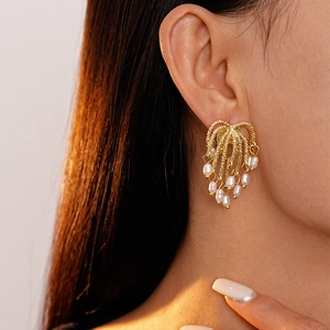 Close-up of golden firework fringe earrings with pearls on a female model
