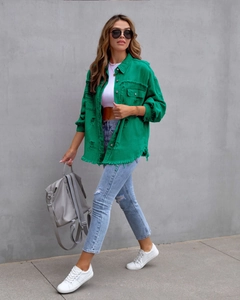 Detail of green distressed denim jacket with frayed edges and vintage wash effect
