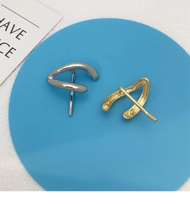 Macro view of minimalist twisted geometric metal earrings in silver and gold finish
