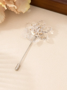 Detailed close-up of a long transparent floral brooch with gold beads and silver needle