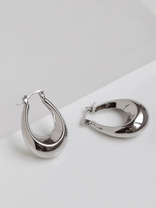 Detailed close-up of polished silver teardrop hoop earrings with high reflective mirror finish